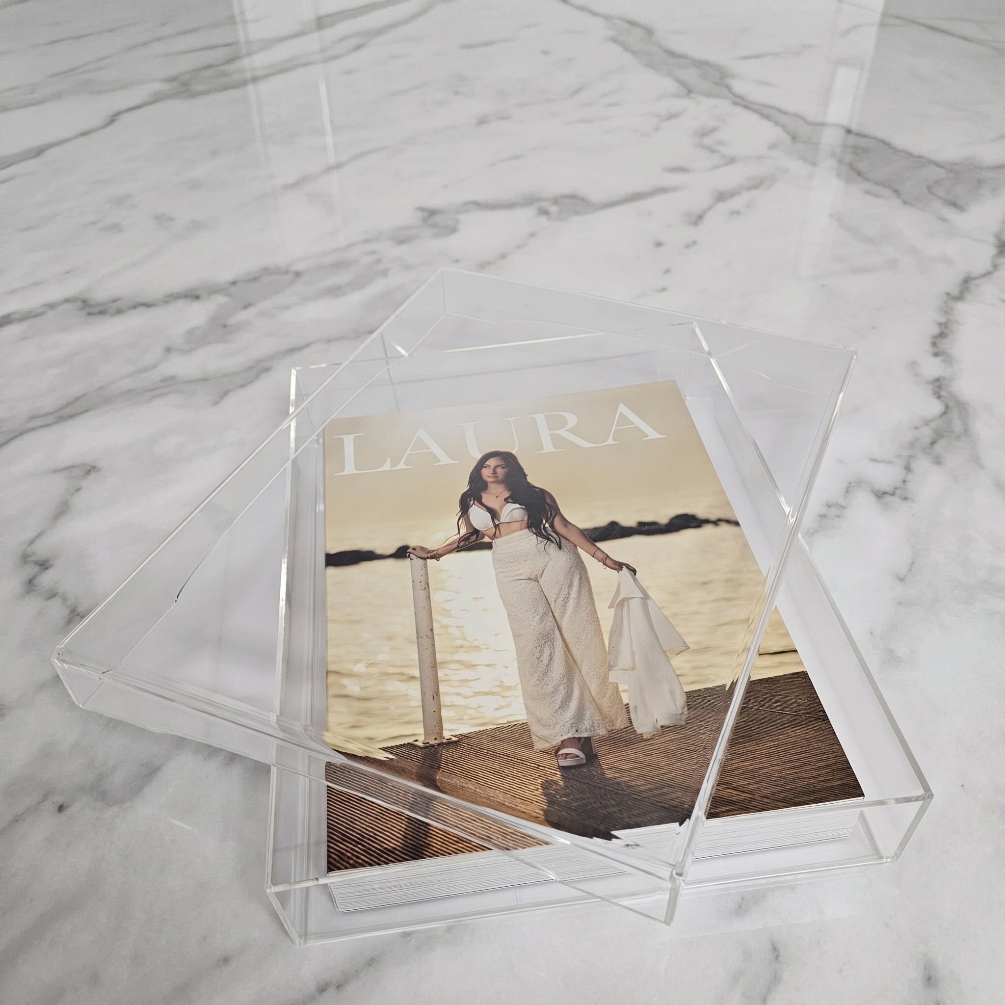 Cofanetto in plexiglass trasparente con album fotografico e supporto verticale coordinato.